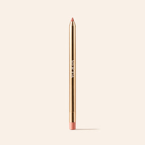 Signature Lip Pencil in Perfect Nude featuring a gold metallic body and pointed tip on a cream background.