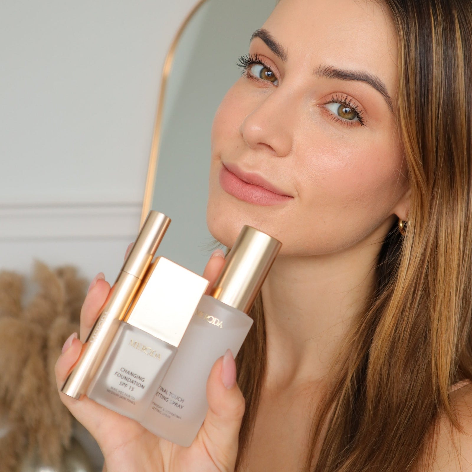 Travel Kit featuring mini Changing Foundation, Final Touch Setting Spray and Gilded Lashes Mascara held by a model.