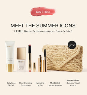 Summer Travel Icons featuring Daily Face SPF 40, mini foundation, lip tint, mascara, and a woven straw travel clutch.