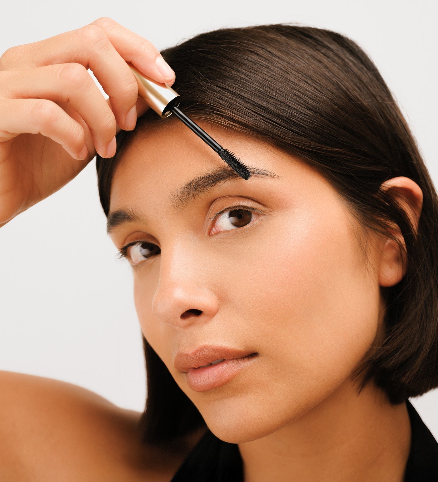 Model applying The Precision Brow Gel to lift and set her eyebrows for a natural, polished look